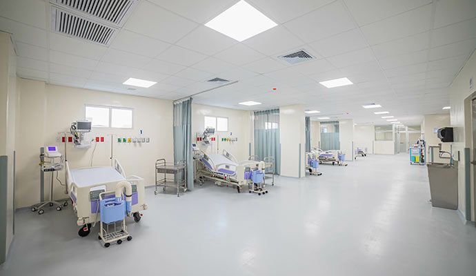 Hospital room with beds, medical equipment, and privacy curtains.