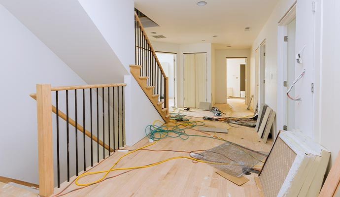 Hallway under construction with staircase, hardwood floors, and exposed wiring.