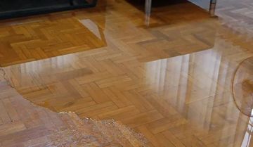 Water pooling on parquet wooden flooring.