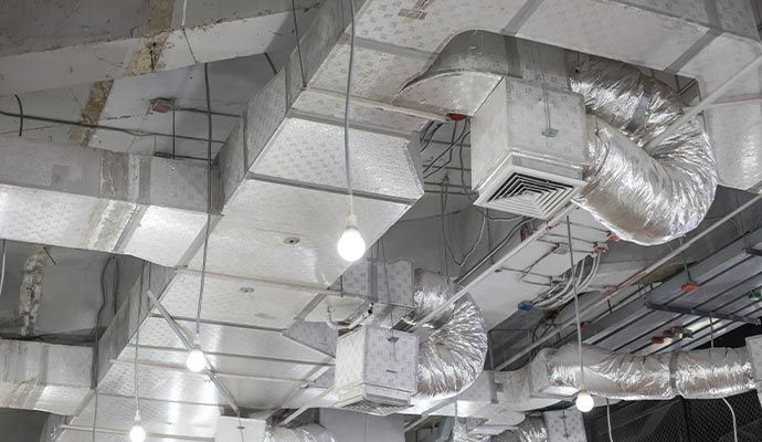 HVAC ductwork and lighting fixtures on a commercial ceiling, metal and reflective.