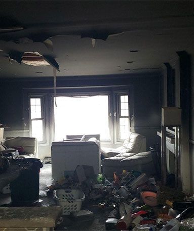 Interior room damaged by fire with debris and hole in the ceiling.