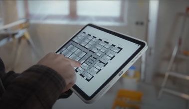Person points at floor plan on tablet in a construction site.
