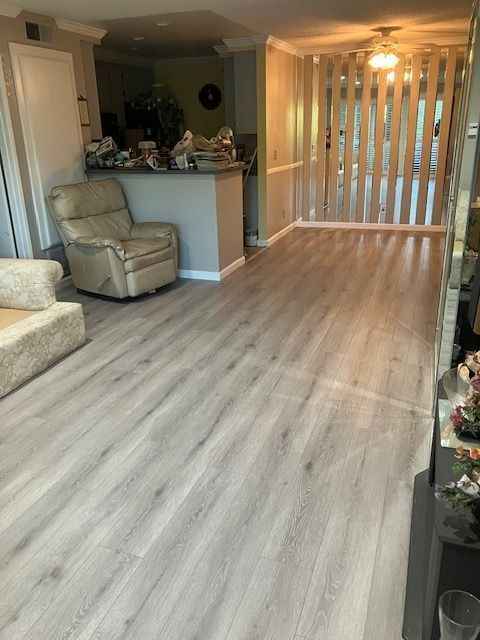 Light gray wood-look flooring in a living space, leading to a half wall with vertical wood slats.