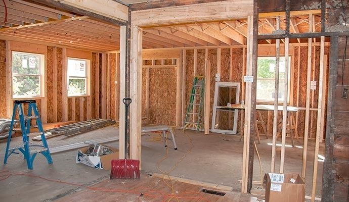 Interior view of a house under construction with exposed wooden framing and tools.