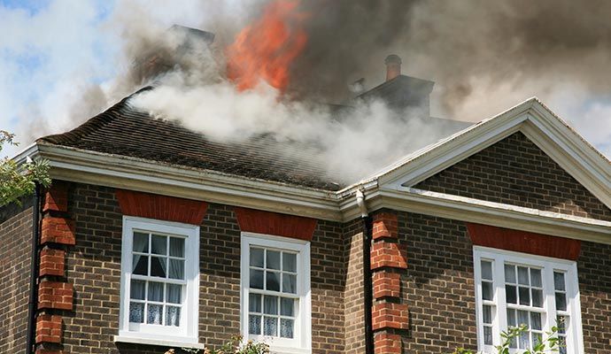 House roof engulfed in fire, smoke billowing into the sky.