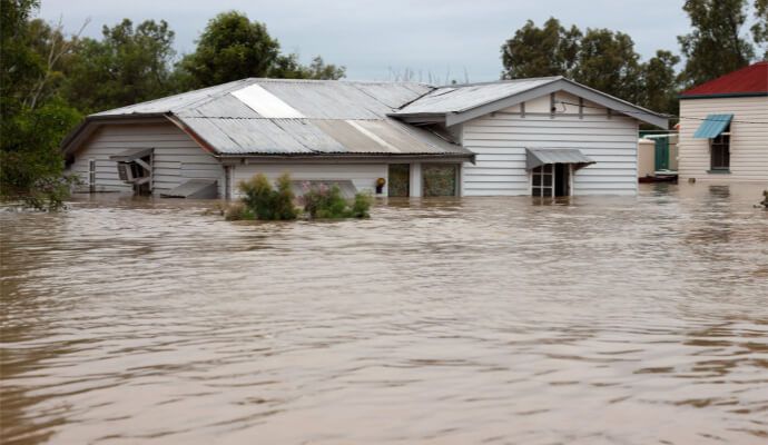 House partially submerged in floodwater, brown water surrounds the building.