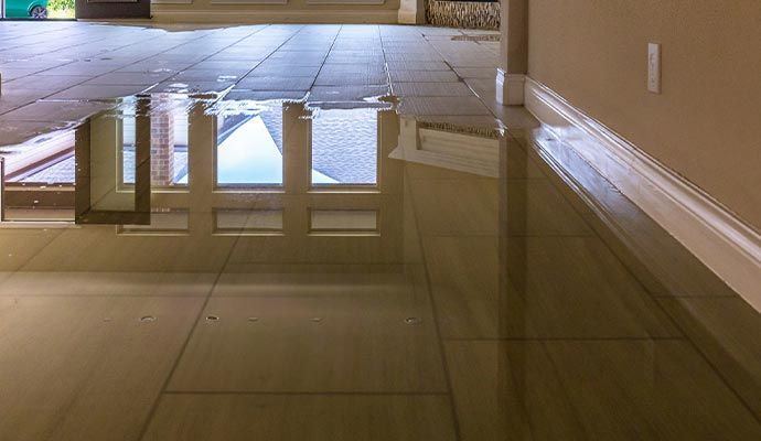 Water on tiled floor, reflecting windows and walls.