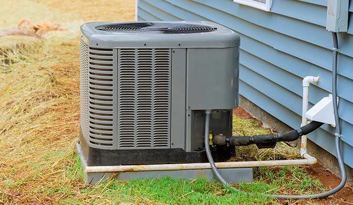 Gray air conditioning unit outside a blue house.