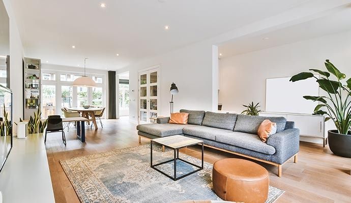 Spacious, modern living room with gray sectional sofa, rug, and dining area.