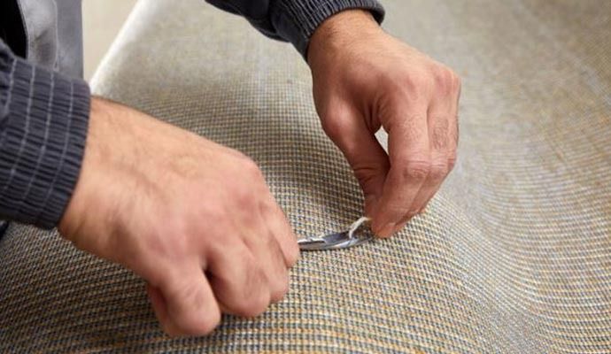 Person using scissors to cut a loop on upholstered fabric.
