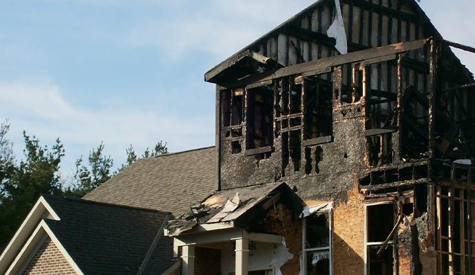 Two-story house with severe fire damage; charred walls, exposed framing.