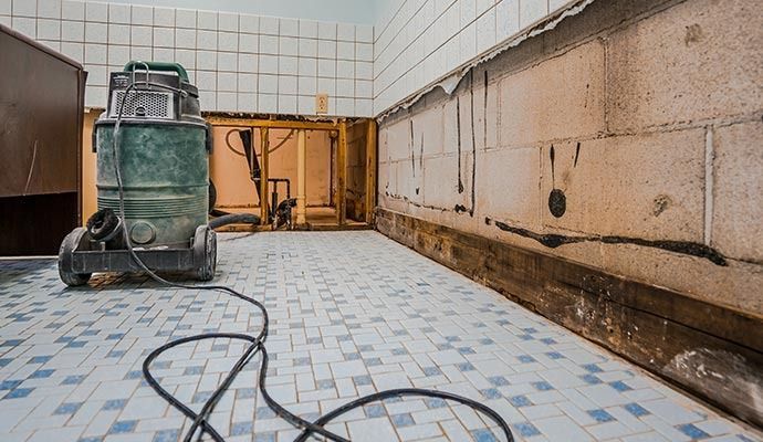 Bathroom undergoing renovation with a wet vacuum, exposed framing, and tile.