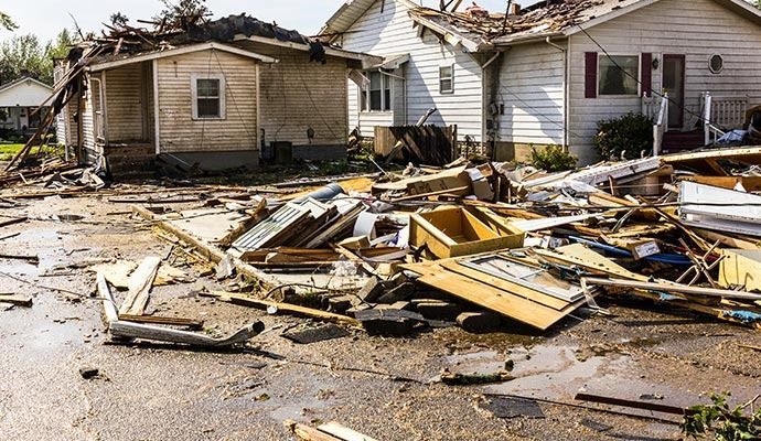 Houses damaged by a tornado, debris scattered across the road.