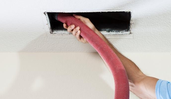 Person vacuuming a dusty air vent.