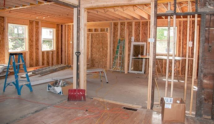 Interior of a house under construction; wooden framing, windows, and equipment visible.