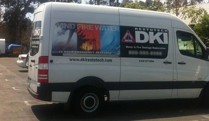White van with DKI logos and graphics advertising fire, water, and wind damage restoration services.