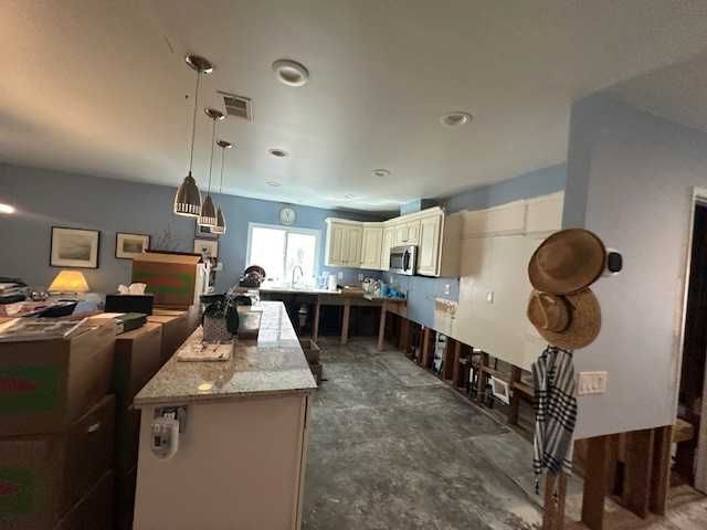 Kitchen undergoing renovation. Cabinets and countertop are present. Damaged walls with exposed studs. Boxes and personal items nearby.