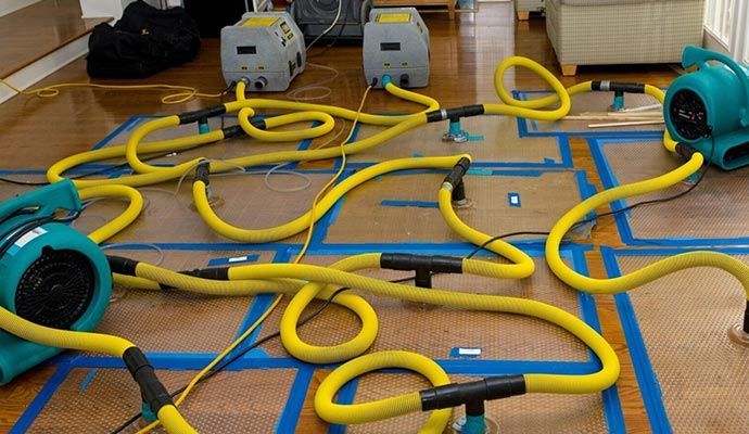 Flood restoration equipment on flooring, drying out a water-damaged area.