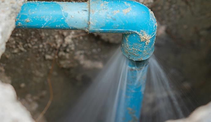 Blue water pipe leaking water in a trench.