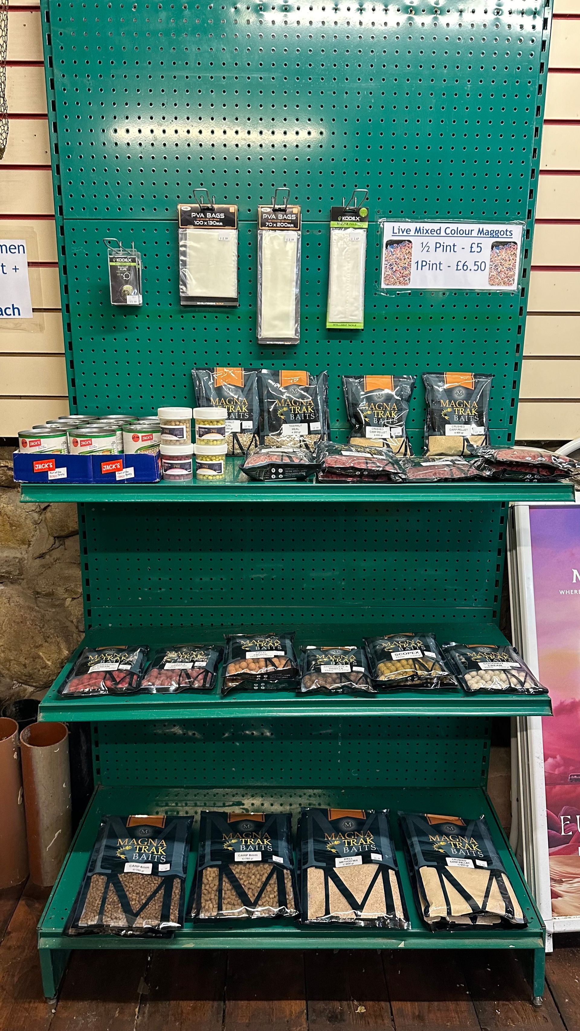 A green shelf filled with a variety of items in a store.