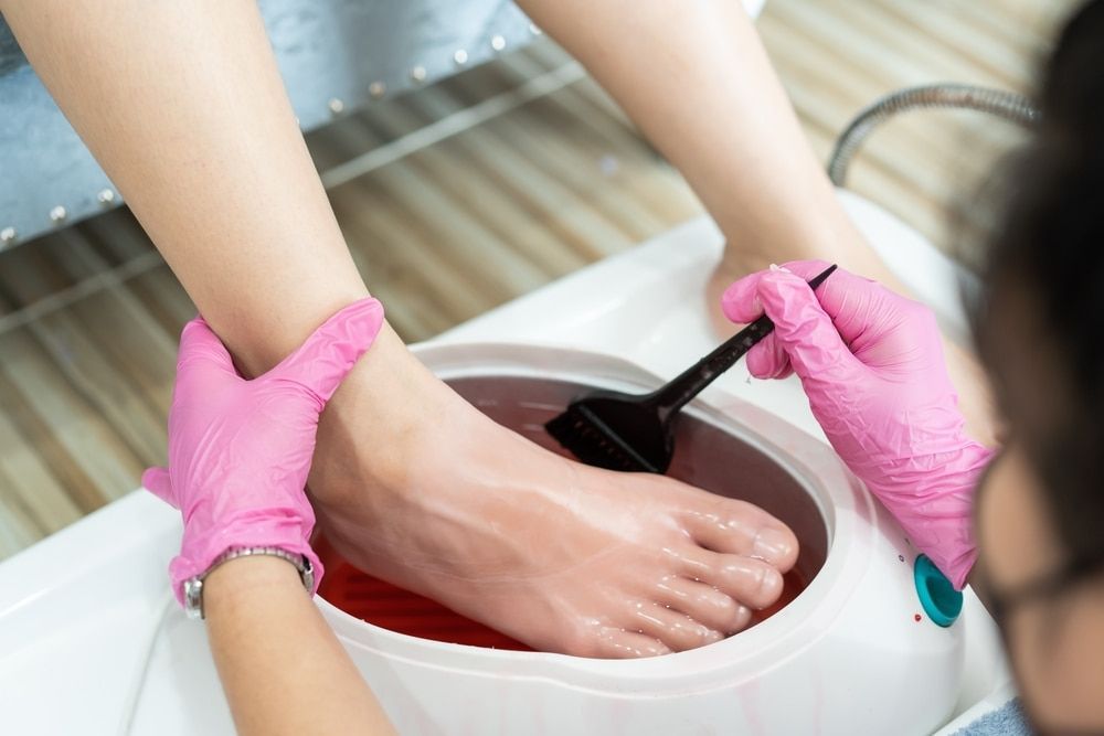 A Woman Is Getting A Paraffin Treatment On Her Feet — Skin Care Centre of Cairns In Cairns City, QLD