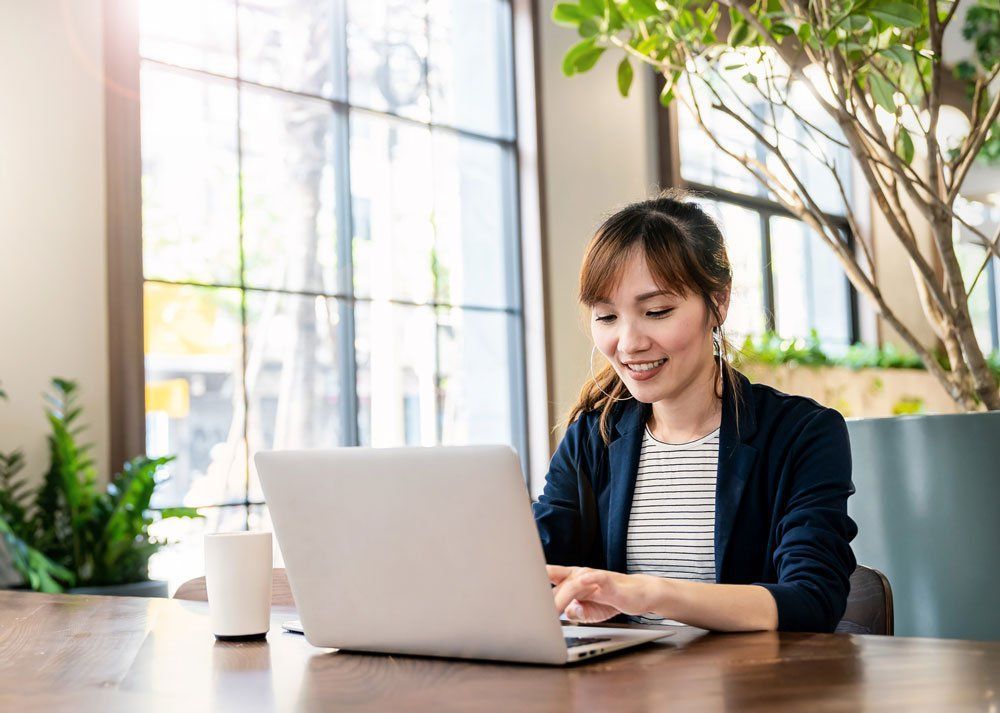 A woman is sitting at a table using a laptop computer.