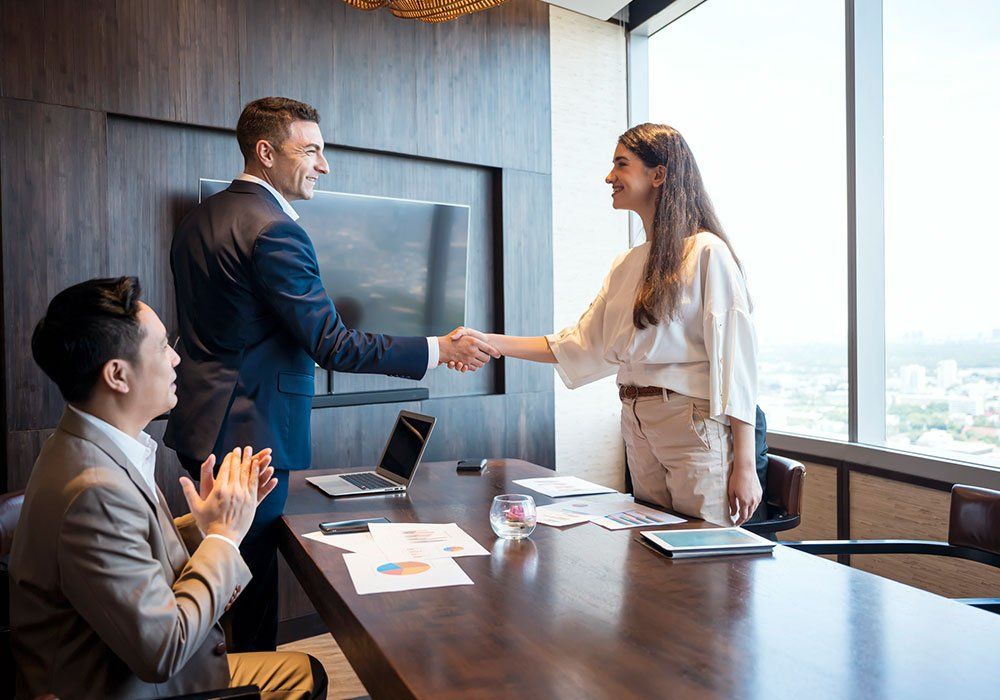 A man and a woman are shaking hands in a conference room.