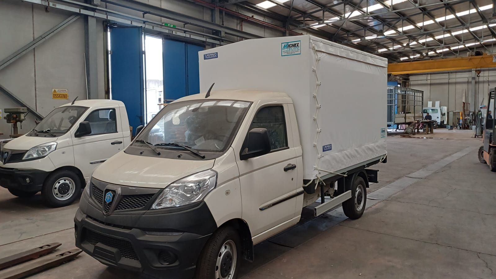 Due camion bianchi sono parcheggiati in un magazzino.