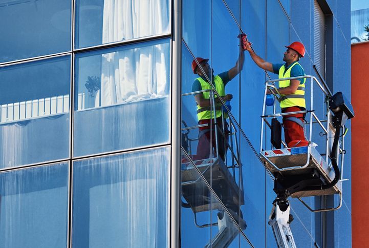 A window washers cleaning the outside of a commercial building during the day.