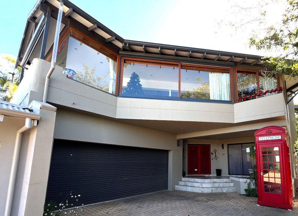 Two-story house with a garage, balcony, and a red telephone booth in the front.