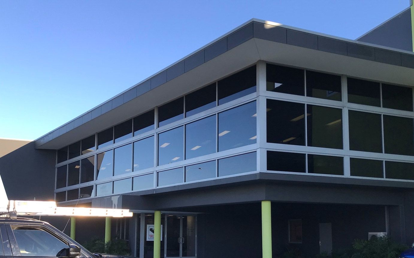 Modern building with large windows and a flat roof, under a clear blue sky.