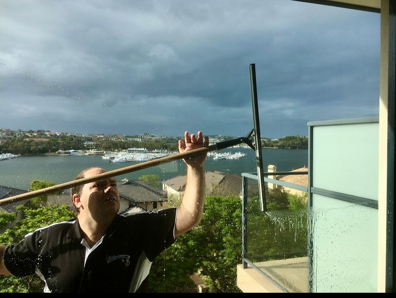 A beautiful young woman cleaning and wiping a window with a spray bottle and blotting paper A beautiful young woman cleaning and wiping a window with a spray bottle and blotting paper