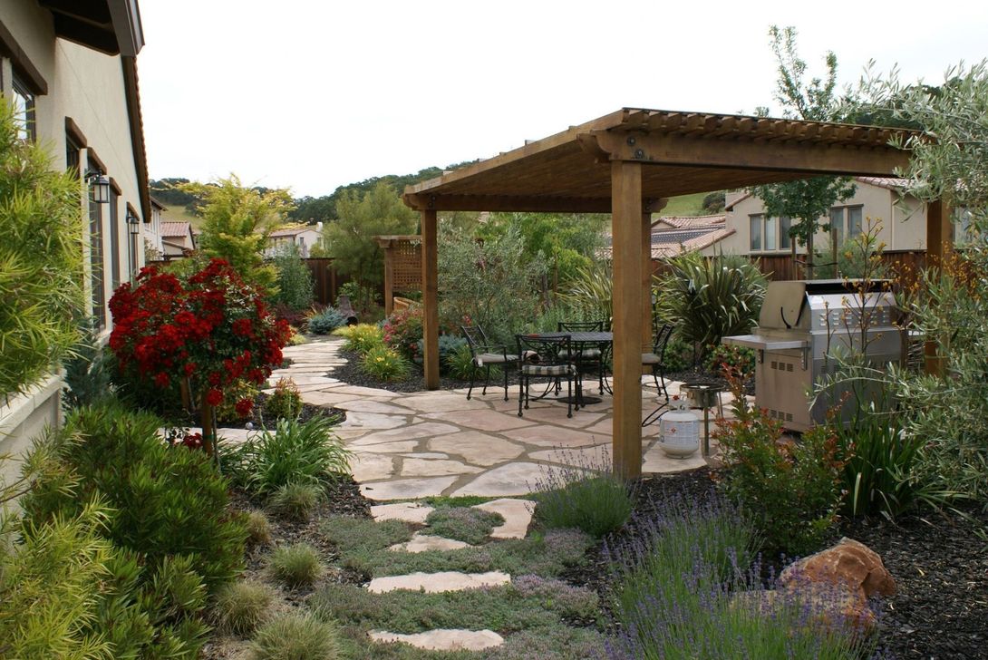 Patio with wooden pergola and a mini garden. Landscaping Design by Turfworks, Inc