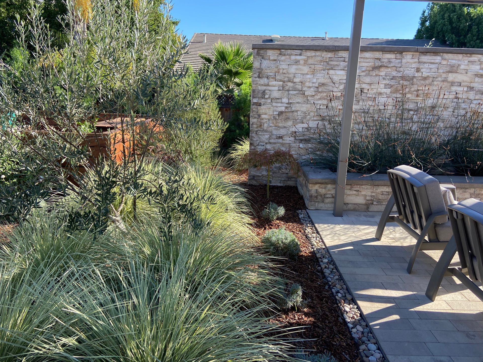 Landscape Design in Vacaville, CA: Well-maintained garden on a patio with chairs and a stone wall by Turfworks, Inc.