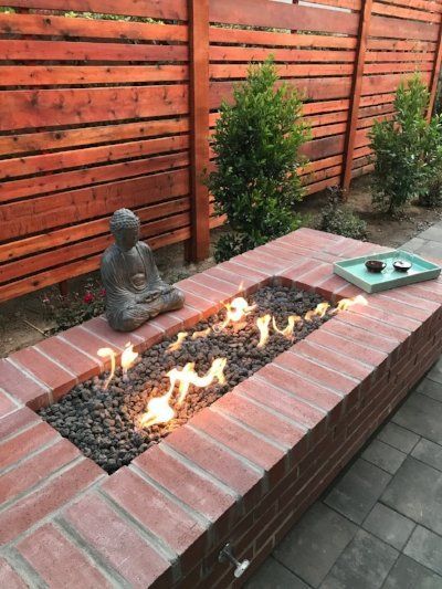 Paver design by Turfworks Inc. with a Buddha statue on a brick platform, surrounded by multi-colored pebbles and greenery