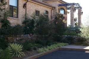 A large stone house with a lot of plants in front landscaped by Turfworks, Inc. | Best Landscaper in Vacaville, CA