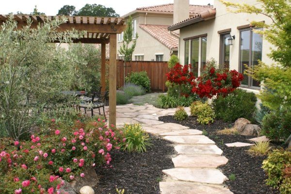 A stone walkway with a pergola and garden of flowers - Turfworks Inc. Landscaping Design in Vacaville, CA
