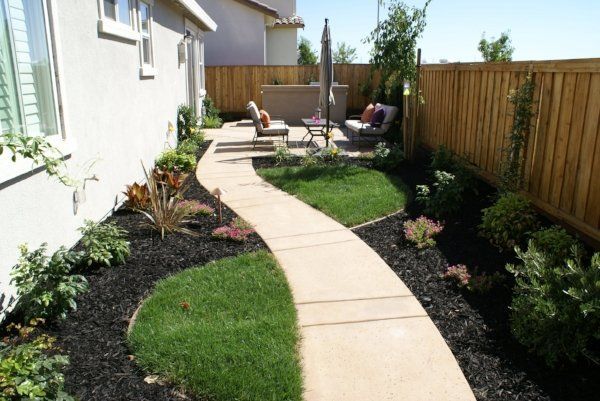 A beautifully landscaped concrete walkway with a wooden fence done by Turfworks Inc. best Landscape Company in Vacaville, CA