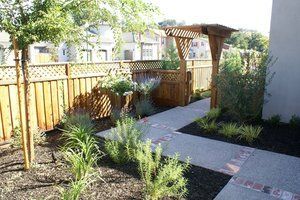 A walkway with a wooden fence and a pergola in the backyard, made by Turfworks Inc. A paver contractor in Vacaville.