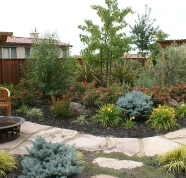 A lush green garden with a fire pit in the middle, landscape design by Turfworks, Inc