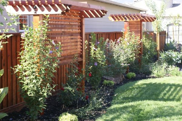 A wooden fence and pergola exude timeless elegance, enhancing the backyard, project executed by TurfWorks, Inc.