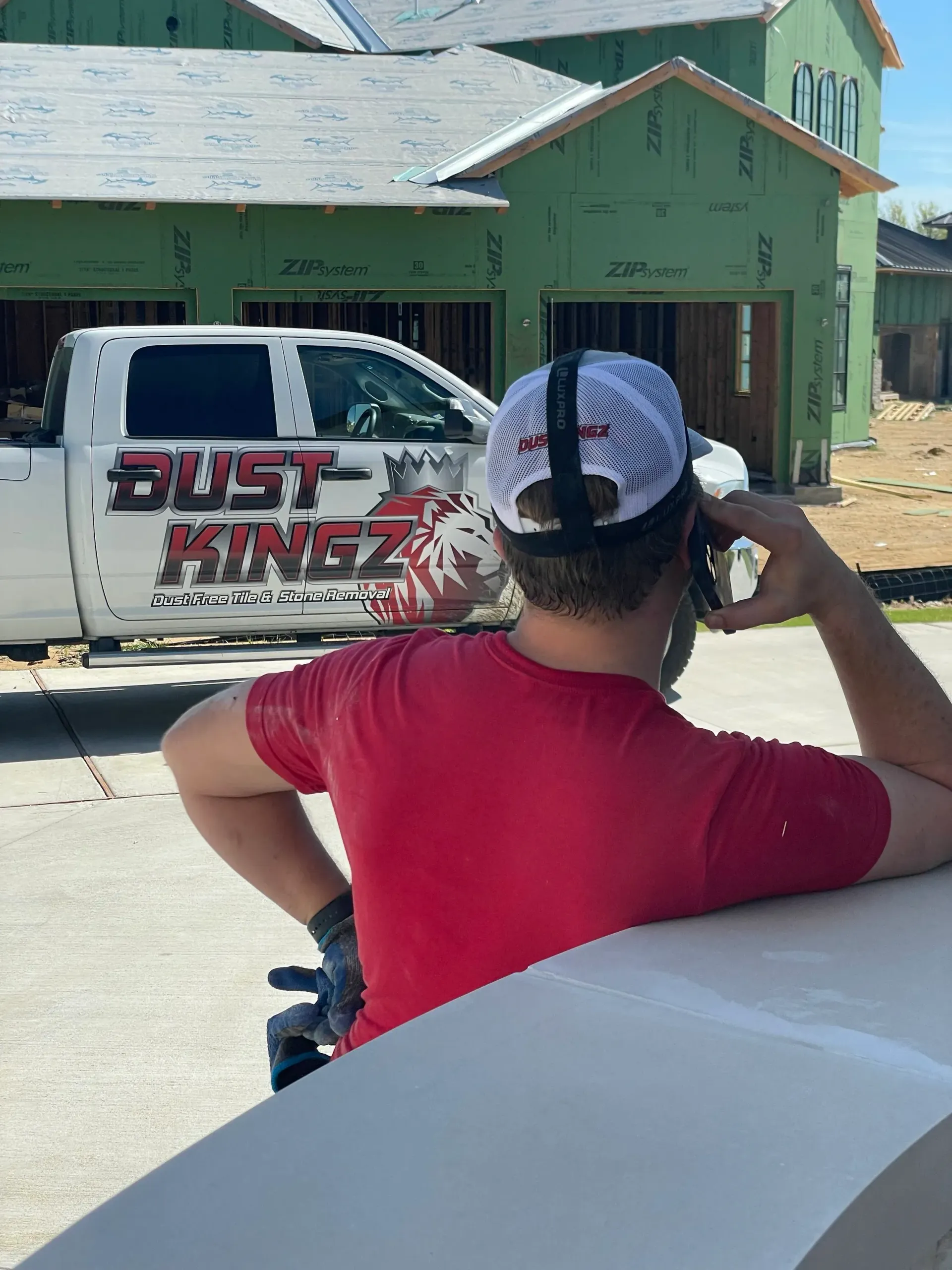 Man in red shirt on phone, standing near white truck with