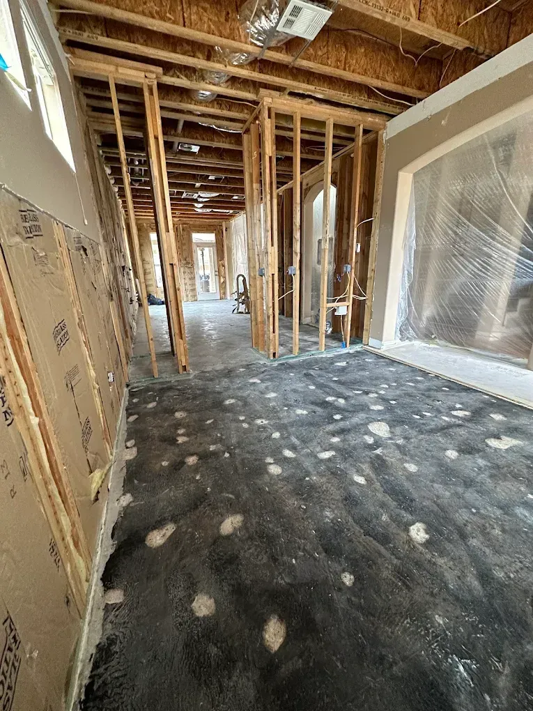 Interior of a building under construction, showing bare wooden frames and black floor.