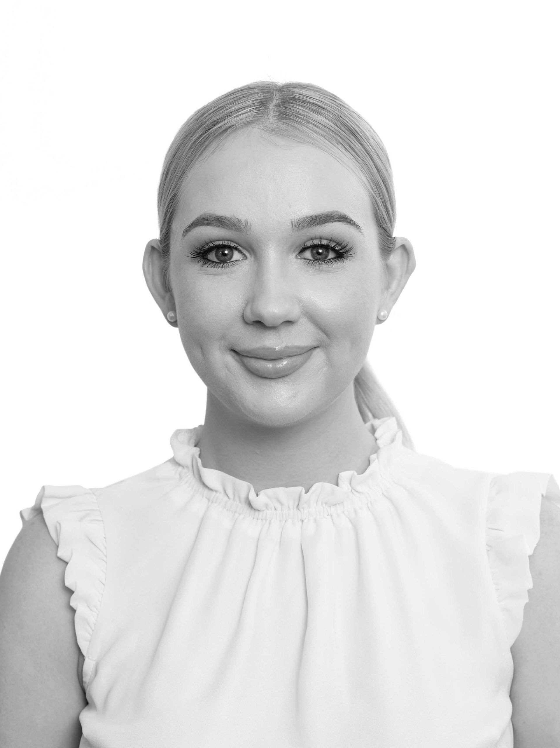 A woman in a white shirt is smiling in a black and white photo.