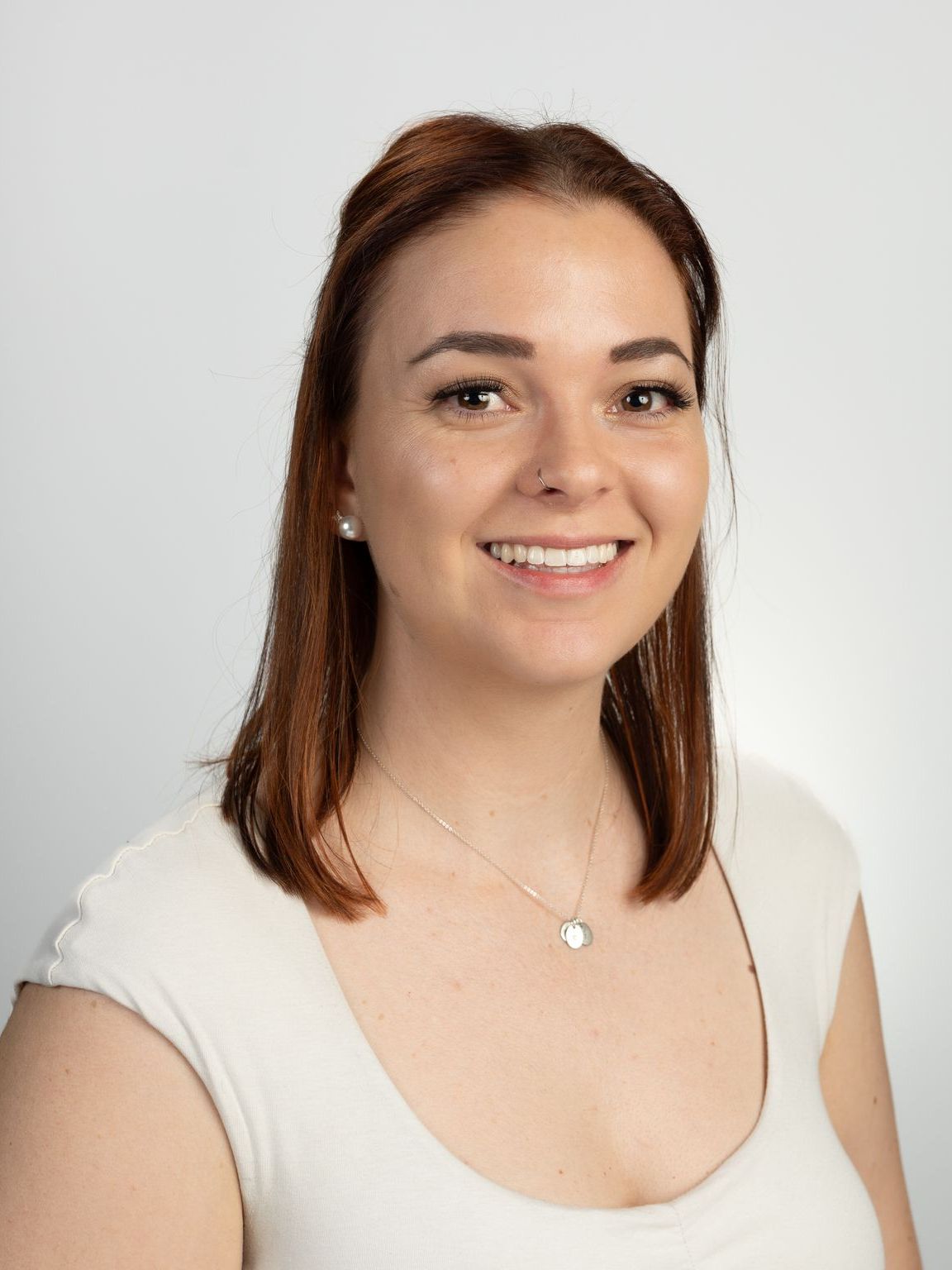 A woman in a pink shirt is smiling for the camera.