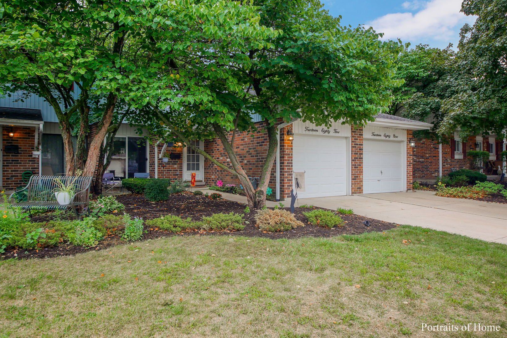 The front of a house with two garages and trees in front of it.
