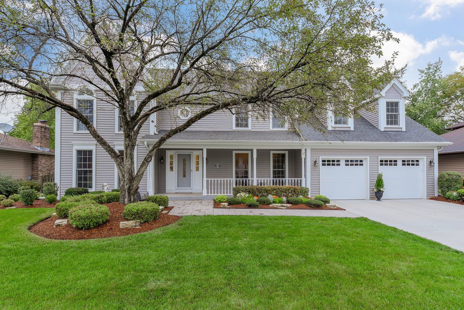 A large house with a large lawn and a tree in front of it.