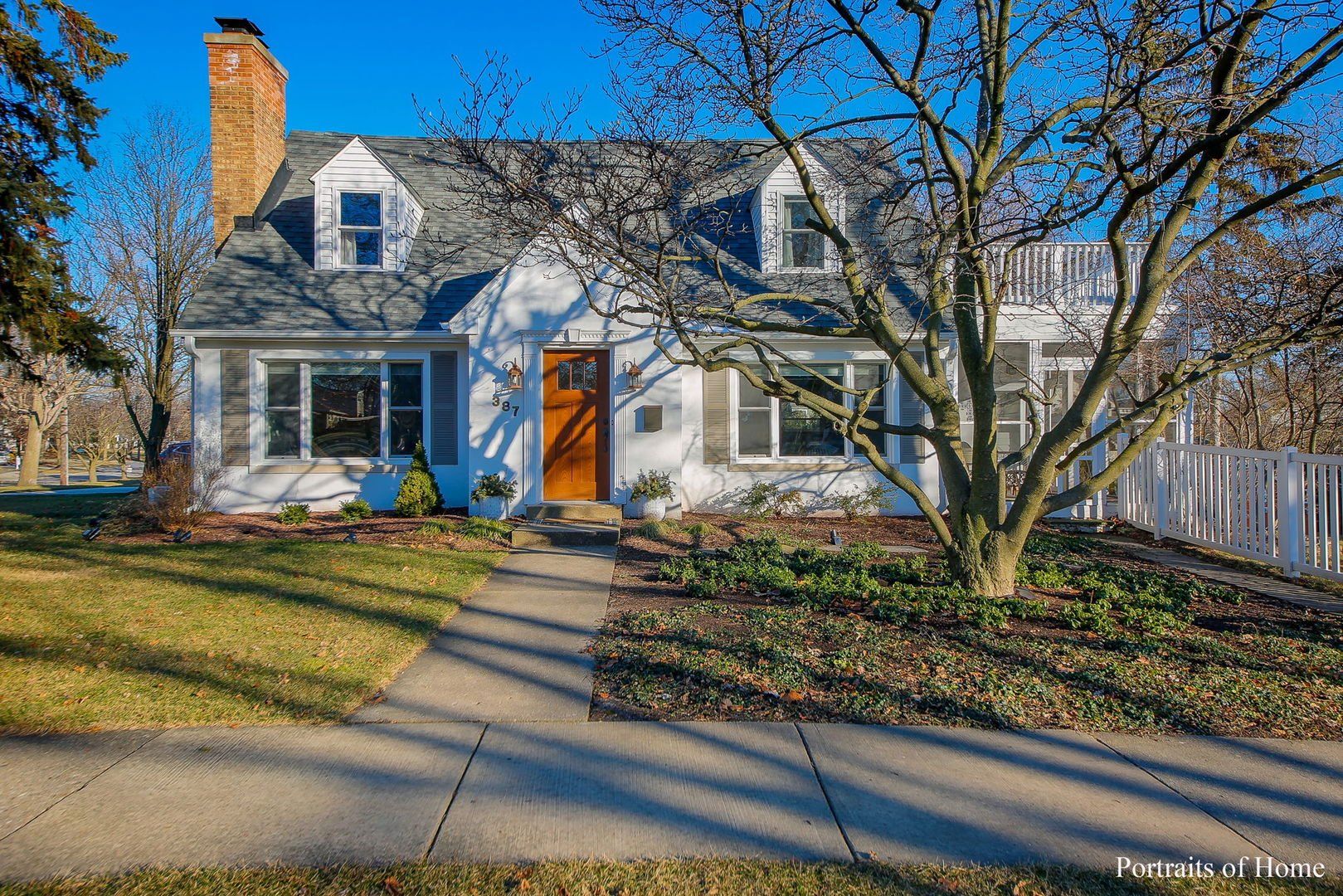 A white house with a gray roof and a brown door is for sale.