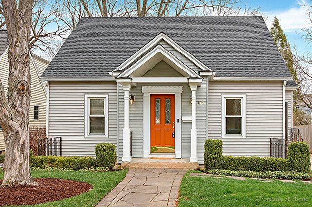 A small house with an orange door and a walkway leading to it.