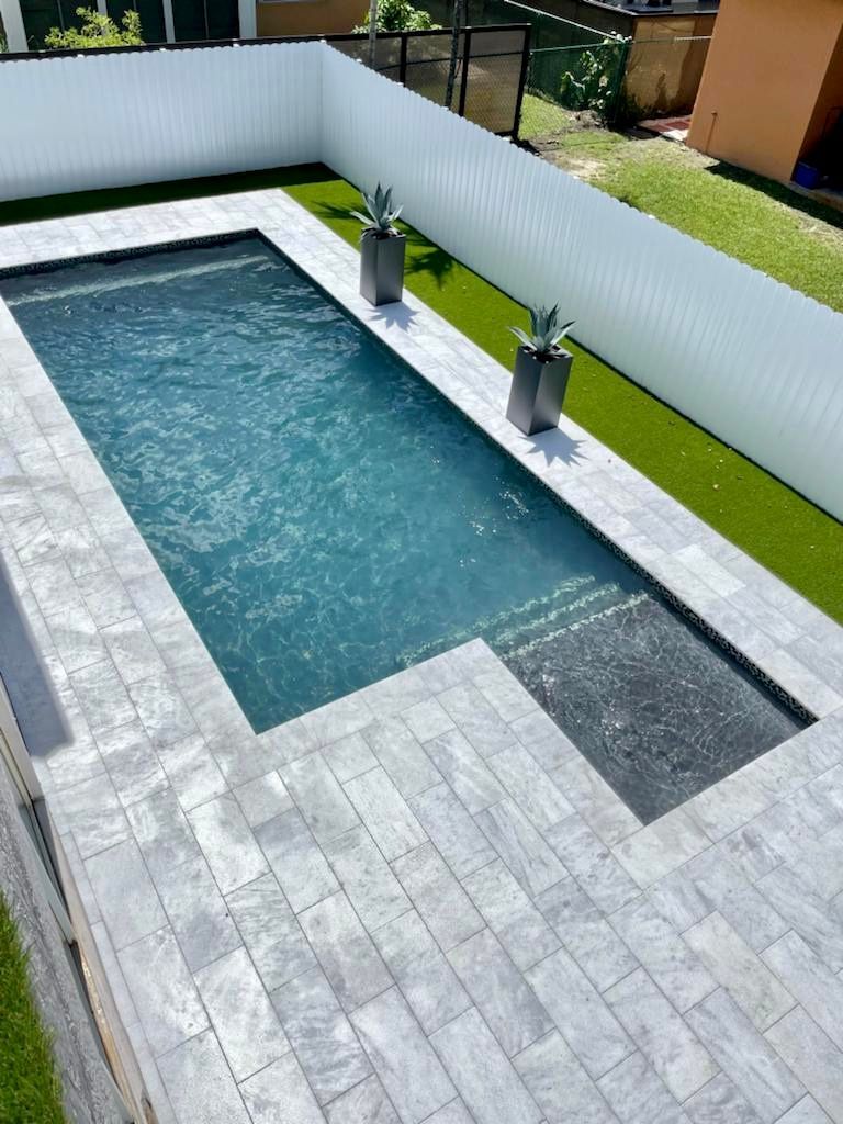 A large swimming pool surrounded by a white fence and grass.